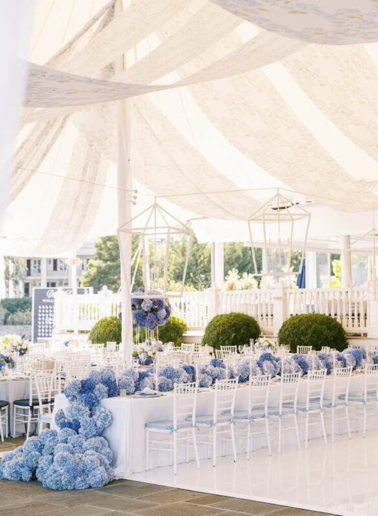 interior de tenda elegante com mesas comunitárias com hortensias azuis