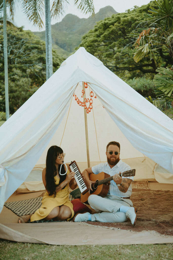 casal tocando música dentro de tenda branca