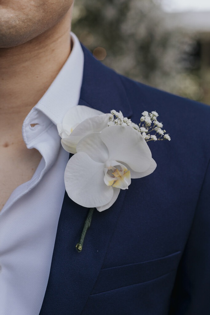 noivo com terno azul e orquidea branca na lapela