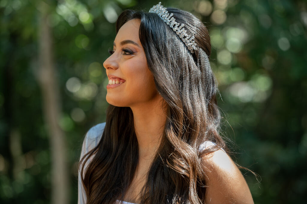 noiva de perfil com cabelo longo ondulado com tiara prateada ao ar livre