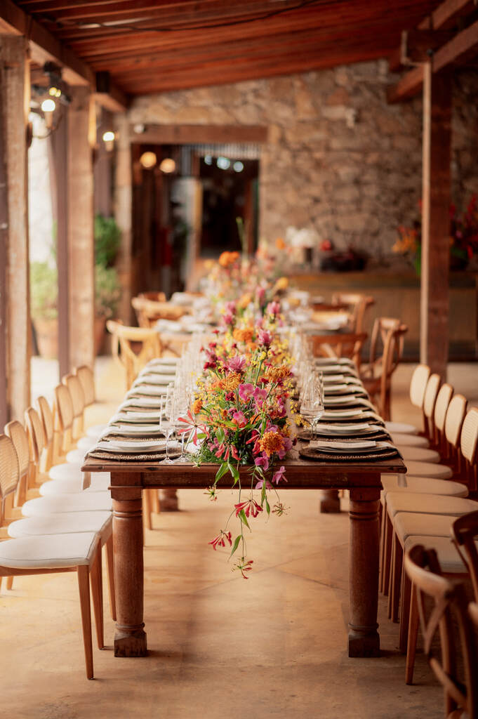 mesa comunitária com arranjo de centro com flores coloridas