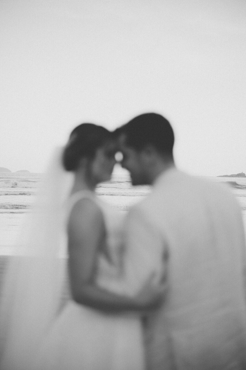 foto desfocada dos noivos se abraçando na praia