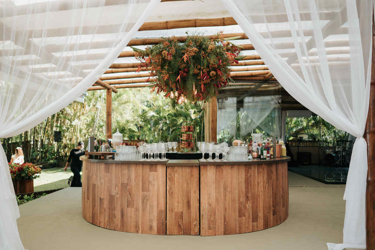 bar com balcão curvo decorado com arranjo aéreo com flores laranjas