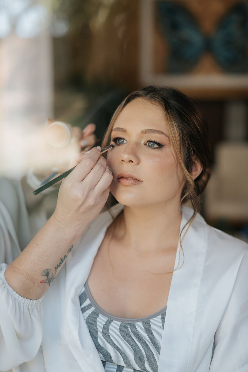 mulher maquiando os olhos da noiva