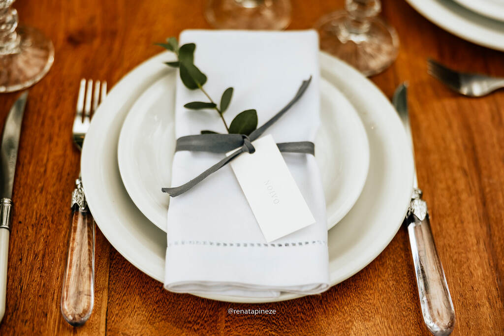 mesa posta com guardanapo branco com folha presa com laço cinza