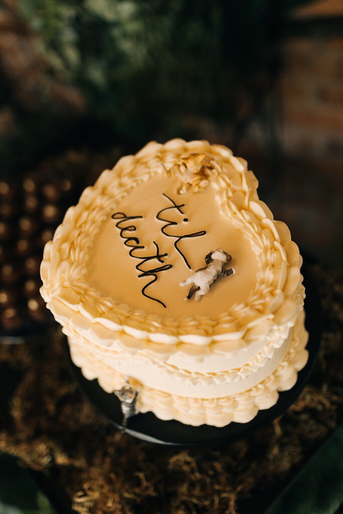 bolo de casamento amarelo em formato de coração escrito til death e miniatura de gatinho