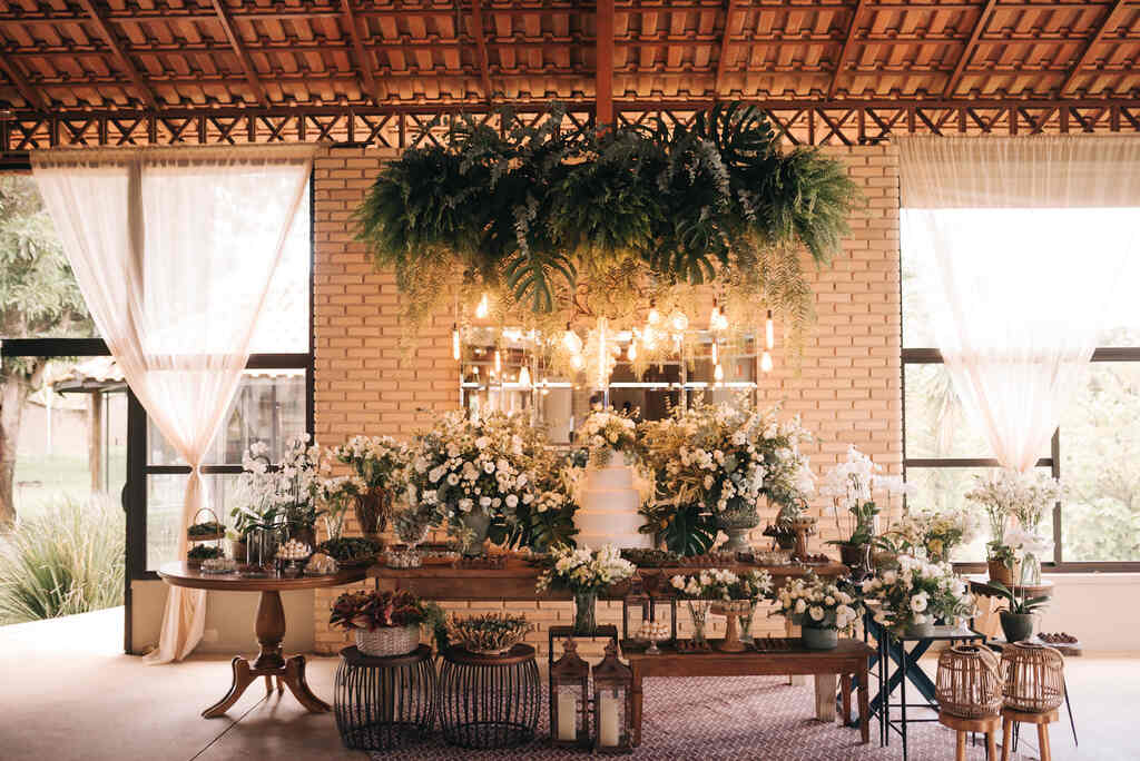 mesa de madeira com boo de casamento com folhagens e flores brancas