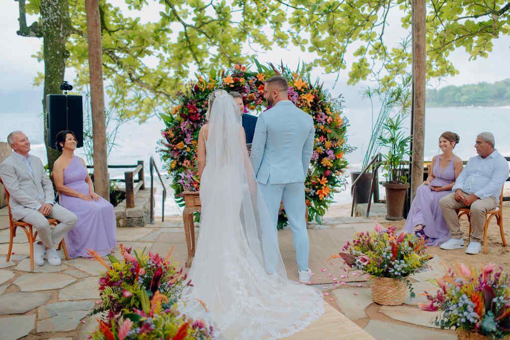 noivos na frente do altar redondo com flores coloridas na praia