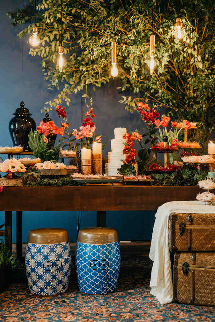 salão azul com mesa de doces de casamento lampadas e bolo branco