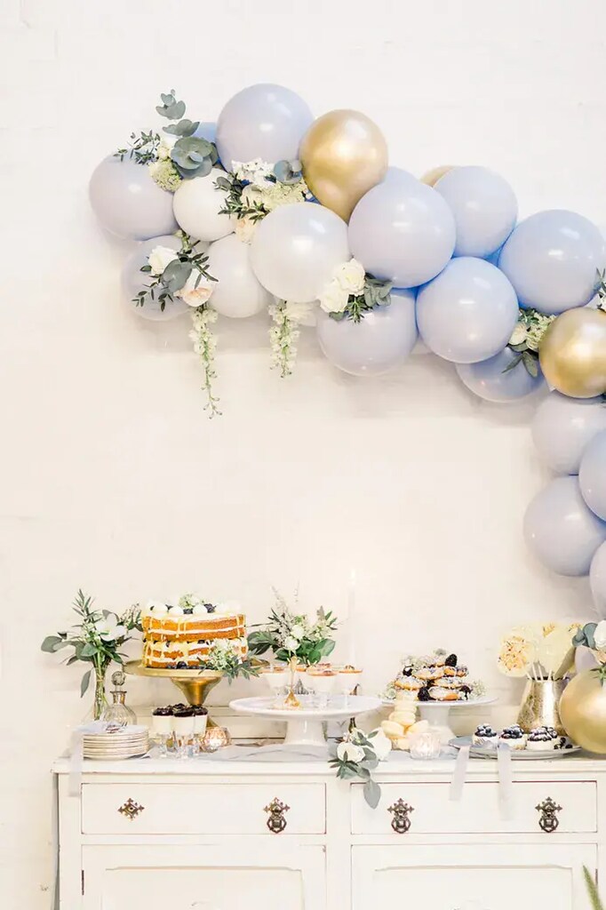 mesa branca com bolo e doces de casamento decorada com bações azuis e dourados