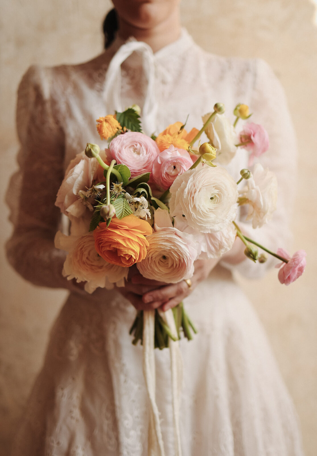 mulher com vestido de noiva vintage com manga longa e renda segurando buquÊ com flores brancas rosas e laranjas