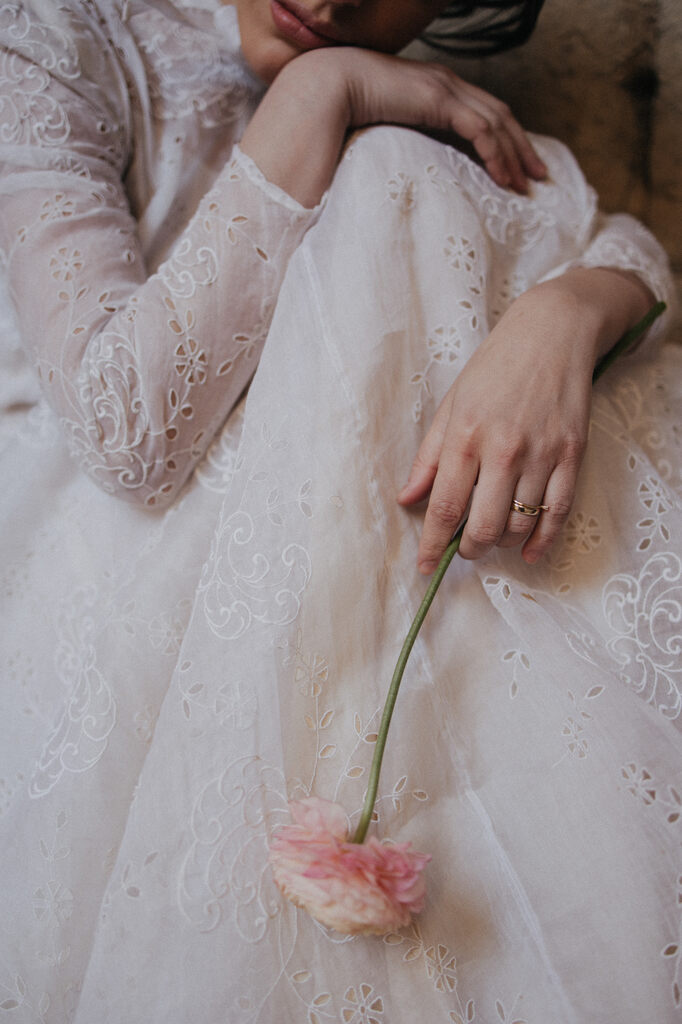 mulher com vestido de noiva vintage segurando flor cor de rosa