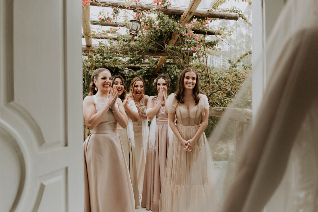 madrinhas com vestidos champanhe reagindo a noiva