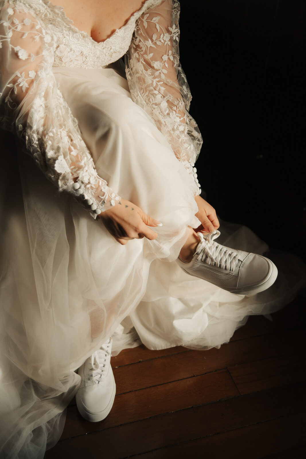 noiva com vestido com manga rendada calçando tênis branco