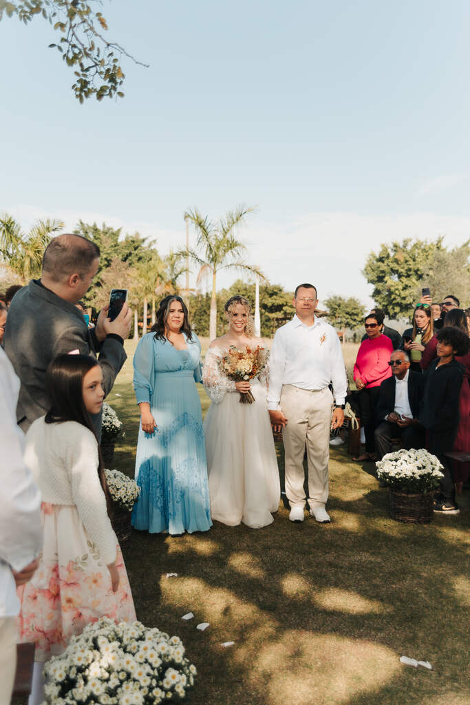 entrada da noiva com ao lado da mãe com vestido azul serenity e pai com camisa branca e calça bege