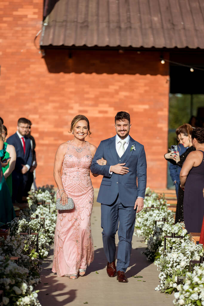 entrada do noivo com terno azul o lado da mãe com vestido rosa claro