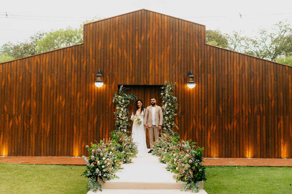 Casal na frente de salão de madeira decorado com flores na saída