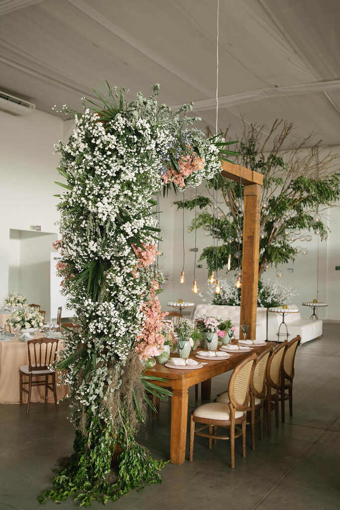 mesa comunitária dentro do salão com aarranjo pendente de flores brancas