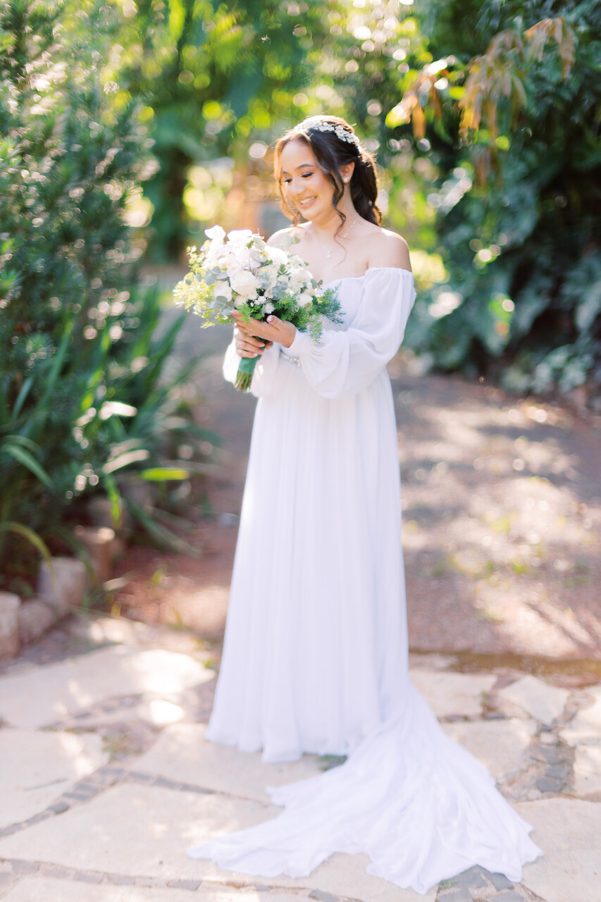 mulher com vestido de noiva minimalista com manga longa segurando buquê branco