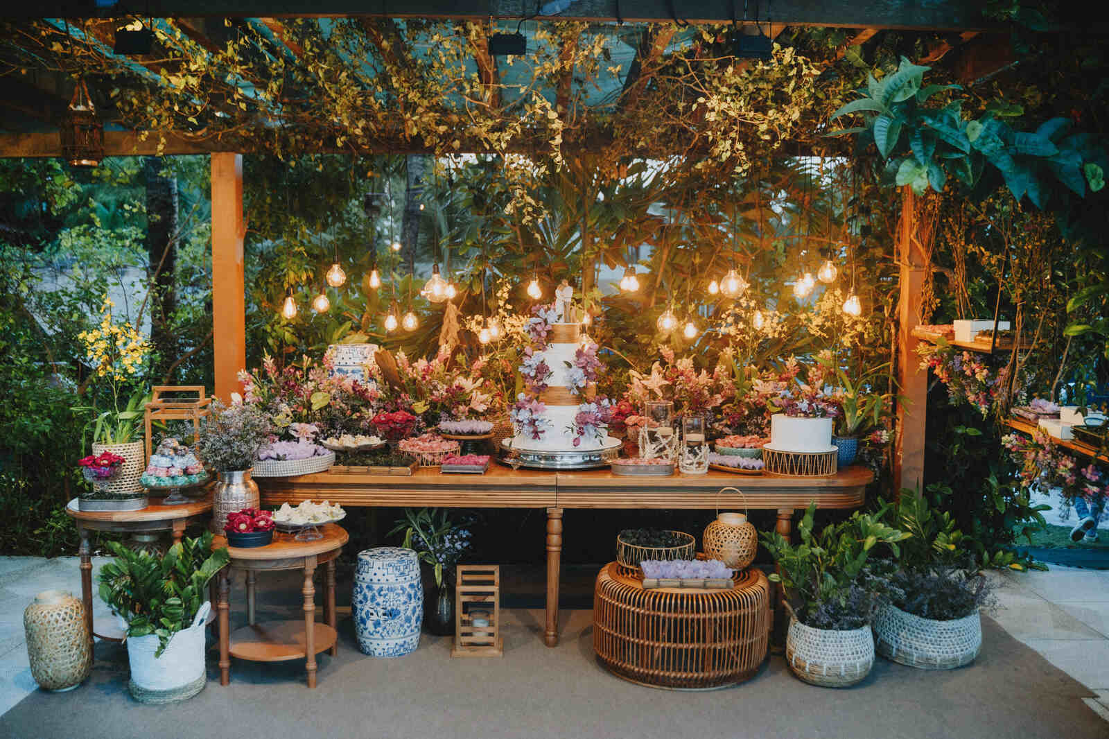mesa para bolo de casamento com flores lilás com luminárias