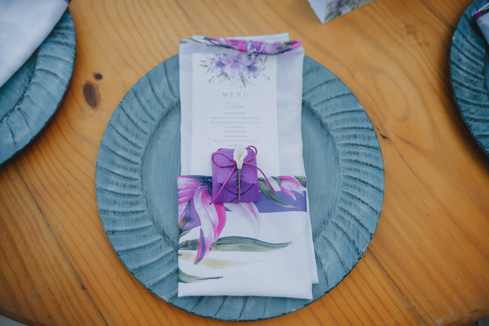 prato azul com guardanapo estampado com folhas e flores lavanda e bem-casado roxo em cima