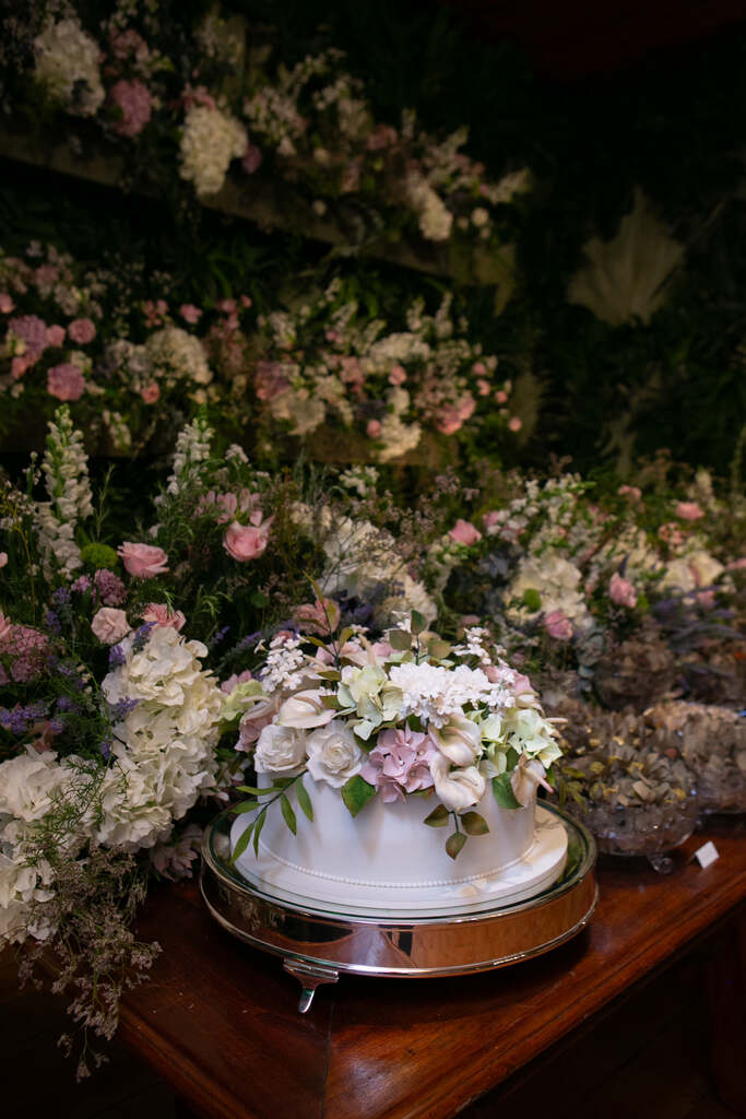 bolo de casamento branco com flores brancas e rosas em cima do bolo