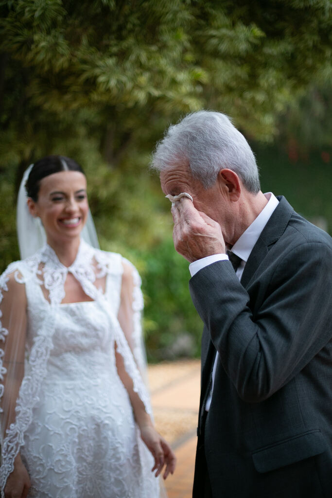 pai da noiva emocionado ao ver a filha com vestido de noiva com capa bordada véu longo ao ar livre
