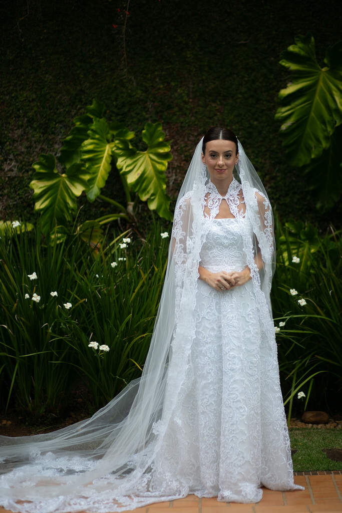 mulher com vestido de noiva com capa bordada véu longo ao ar livre