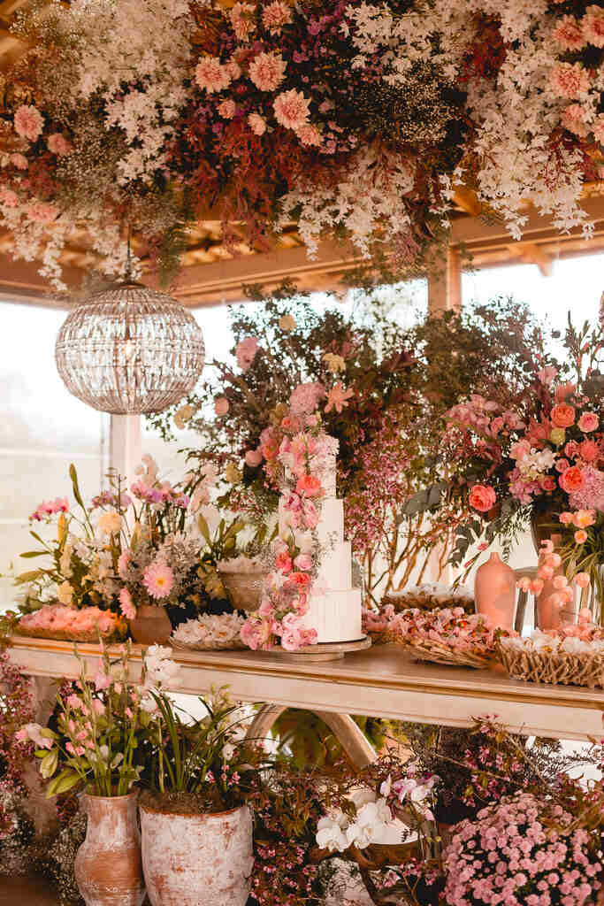 mesa com bolo de casamento com flores amarelas rosas e roxas e flor mosquitinho branca