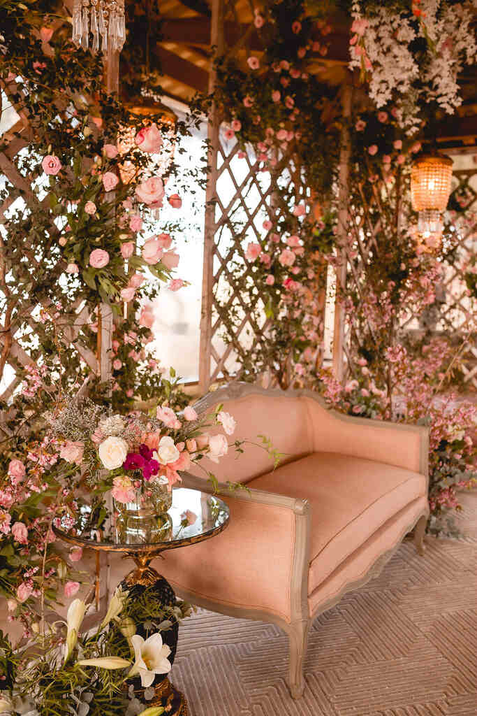 lounge ocm sofá rosa e atrás arco com flroes de rosa