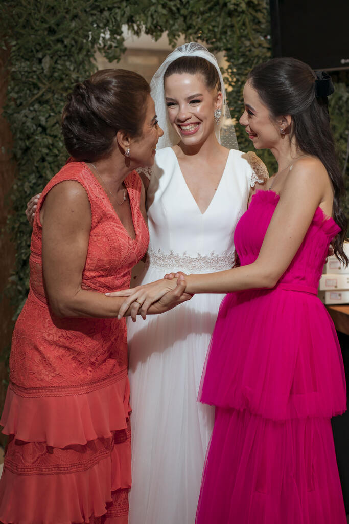 noiva abraçada com duas mulher com vestidos cor de rosa