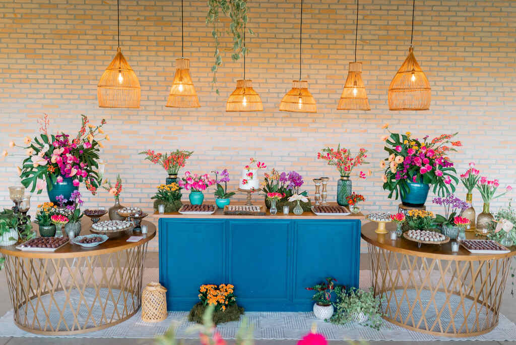 salão rústico com mesa azul com bolo e flores coloridas