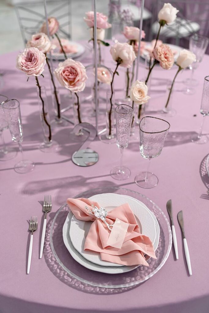 mesa posta com toalha rosa e centro de mesa decorado com rosas