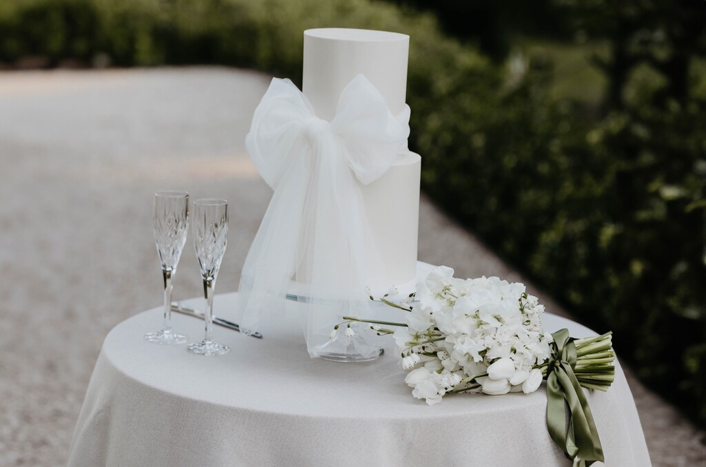 Mesa redonda branca simples com bolo de casamento com laço ao ar livre