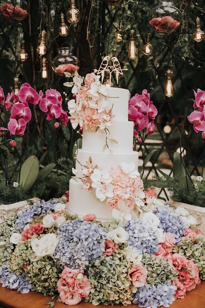 mesa com bolo de casamento decorado com orquideas brancas