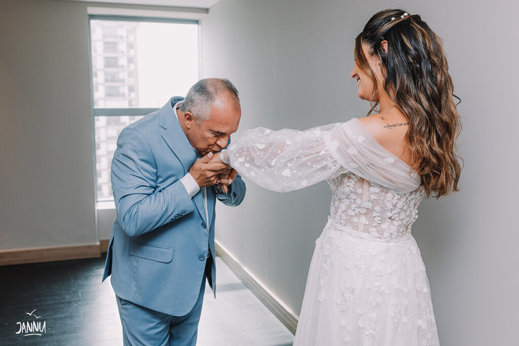 pai da noiva com terno azul claro beijando a mão da noiva de first look