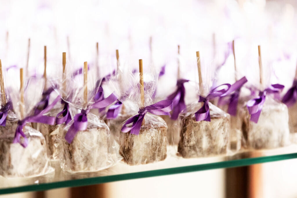 Mesa com doces finos para casamento com palha italiana como lembrancinha e doce fino para casamento com lacinho roxo