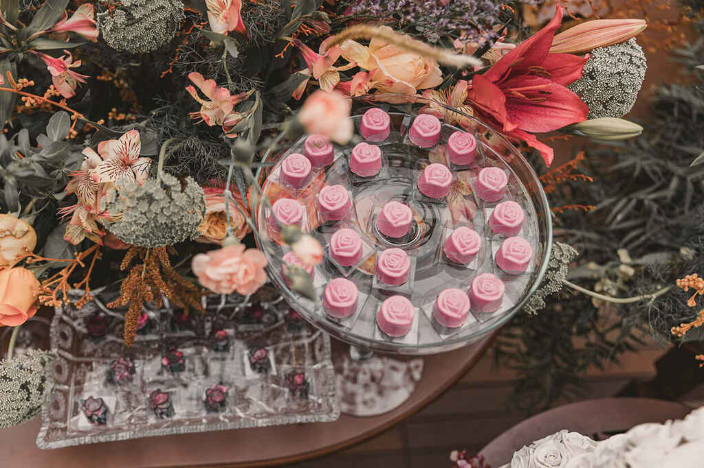 mesa com plantas e flores e bandejas com doces finos para casamento