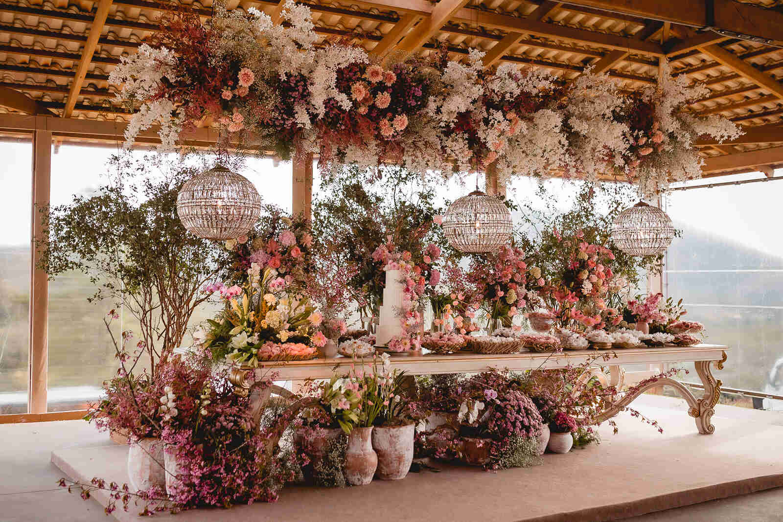 mesa com bolo de casamento com flores amarelas rosas e roxas e flor mosquitinho branca