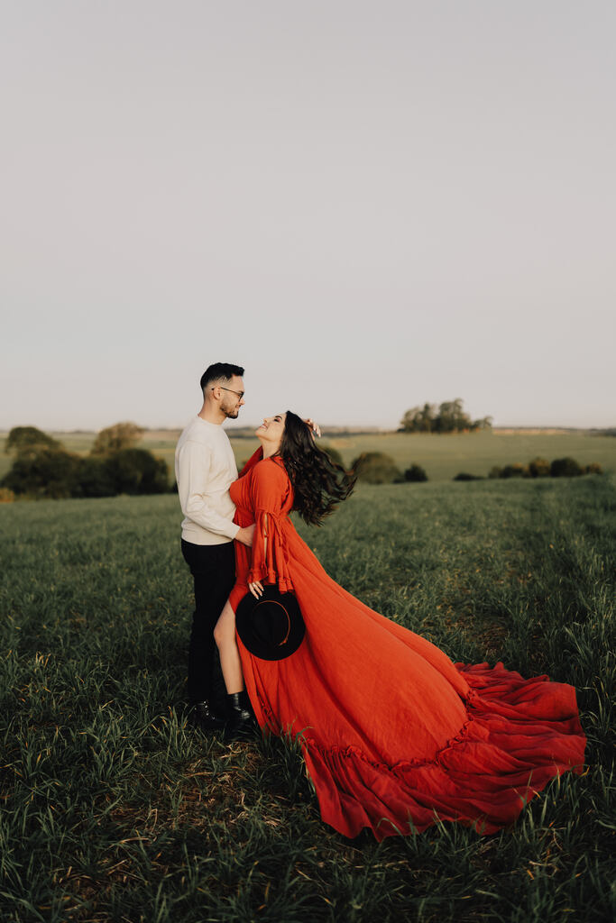 noivaa com vestido terracota longo abraçada com o noivo no campo