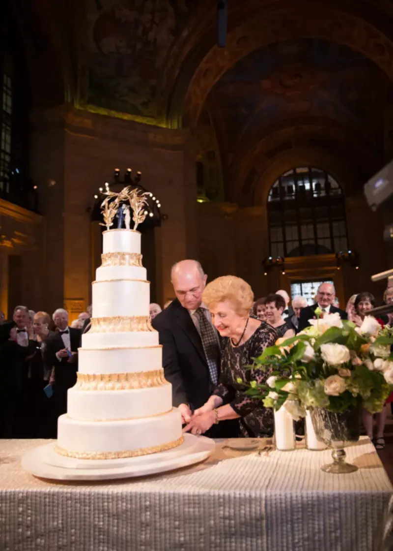 casal cortando o bolo em festa de bodas de ouro