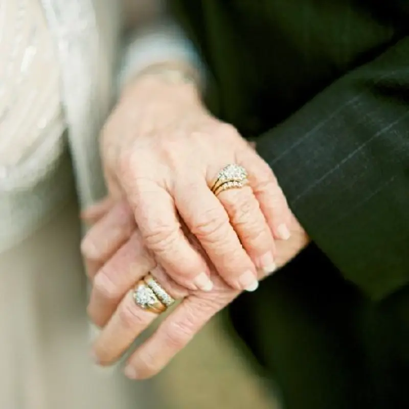 casal segurando ás mãos mostrando as alianças