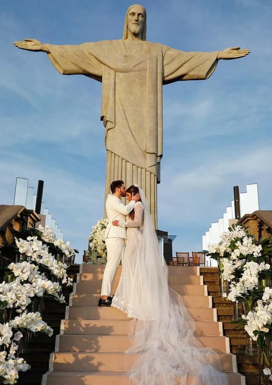 Noivo beijando testa da noiva aos pés do Cristo Redentor
