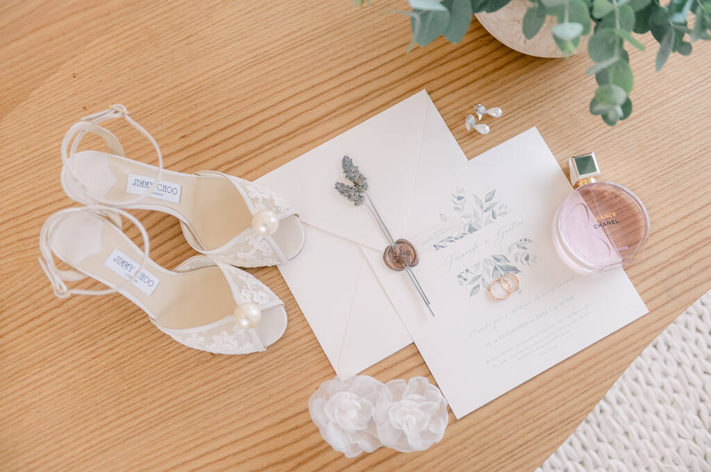 sandália de noiva branca com pérola na ponta ao lado do convite