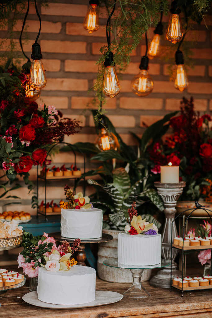 mesa com trio de bolos com topo de flores