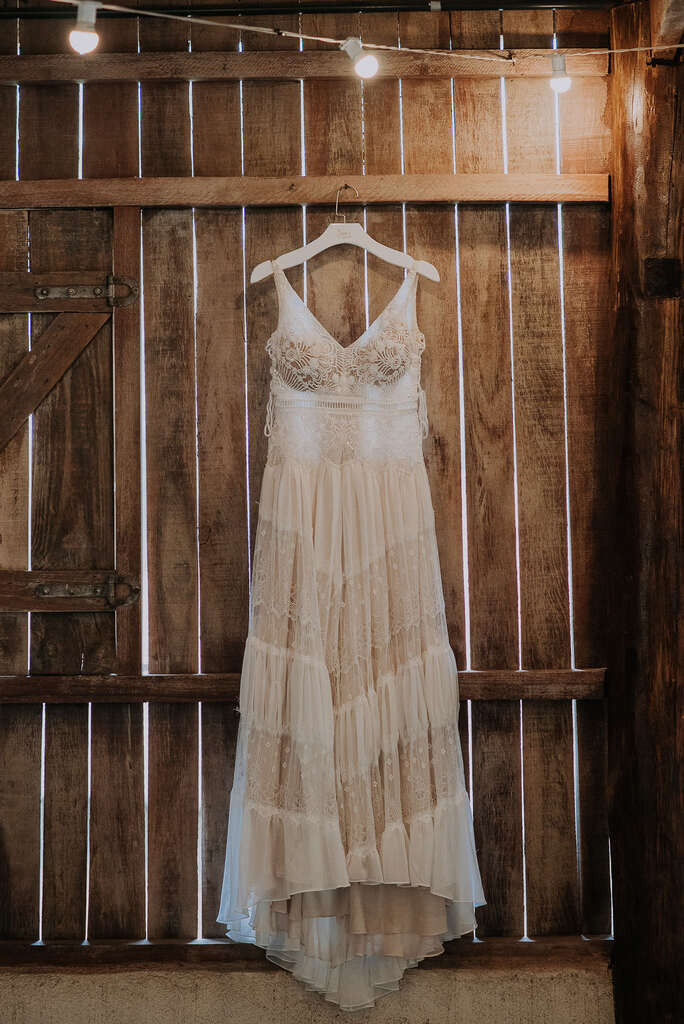 vestido de noiva boho com decote em v rendado pendurado no cabide dentro da caban de madeira