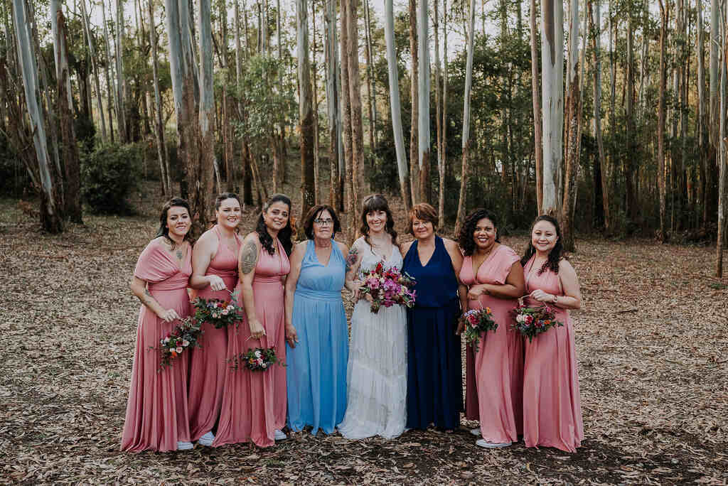 noiva ao lado das mães com vestidos azuis e madrinhas com vetsidos cor de rosa