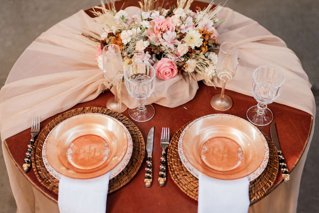 mesa redonda dos noivos com tecido rosê buquê e pratos na cor pêssego