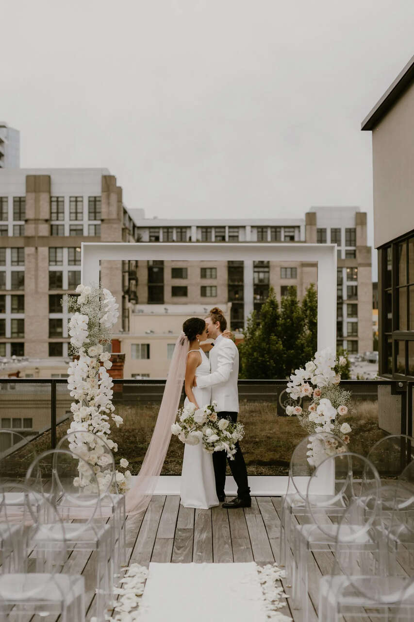 Casal de noivos se beijando em frente ao altar em um cenário urbano