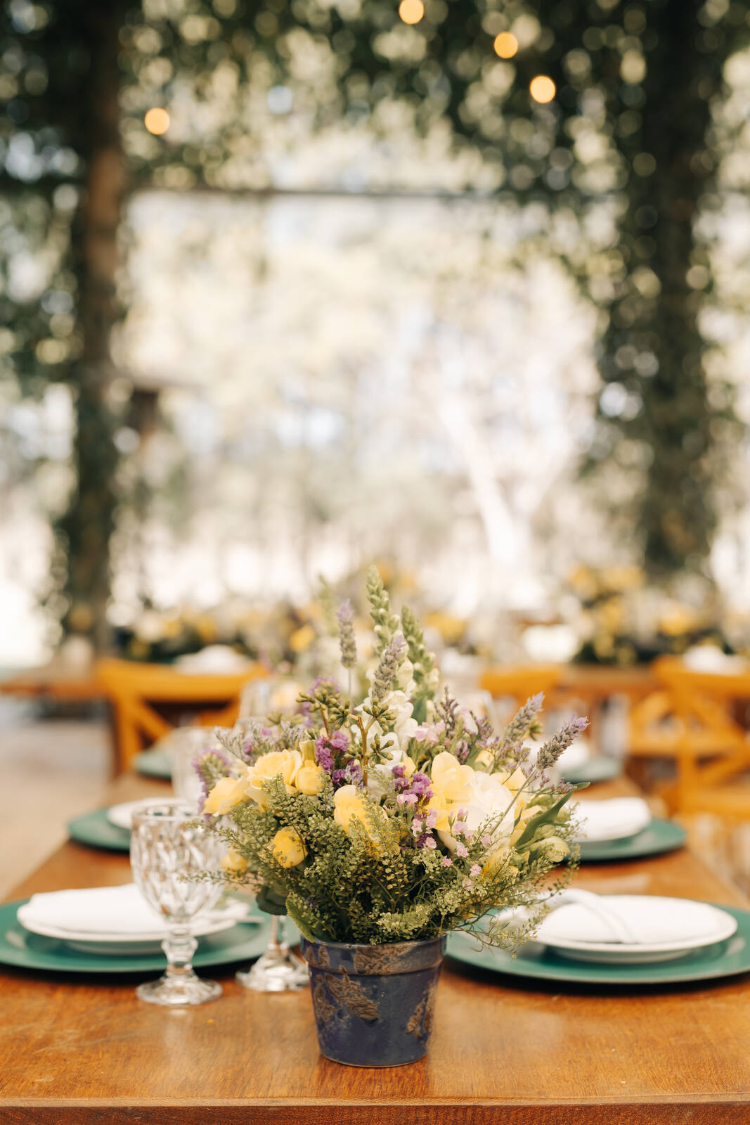 centro de mesa com vasos de flores amarelas brancas e lavandas